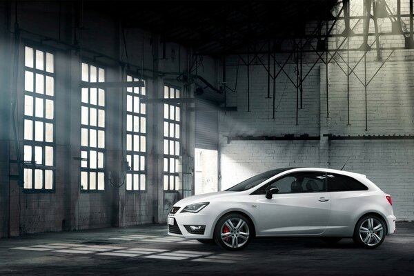 A white car in a room with large windows