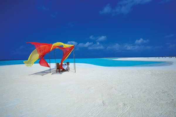 Table romantique sur une plage déserte avec du sable blanc et une mer bleue