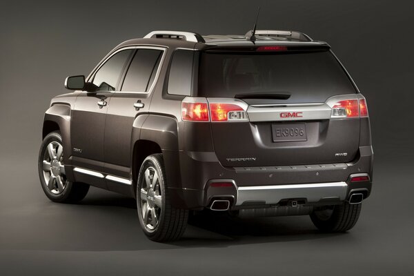 On a gray background, a brown Gmc car is standing backwards