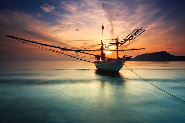 El océano con un barco impregna la puesta de sol roja