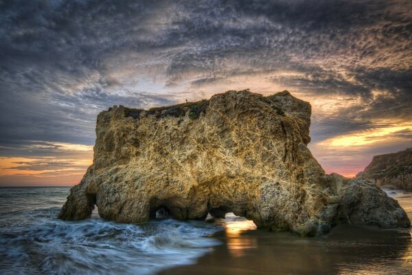 Las olas del mar se rompen contra las rocas al atardecer