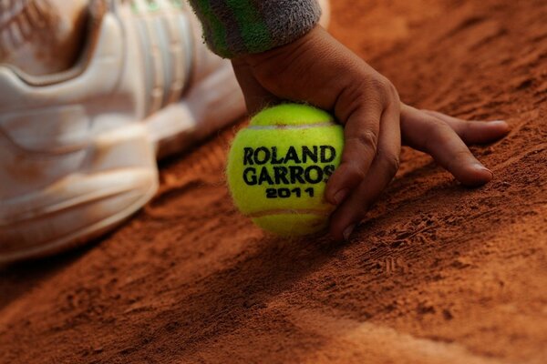 Детская рука. держащая теннисный мячик с турнира Roland Garros 2011