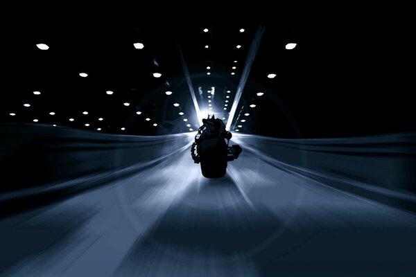 Flying along the black tunnel, along the rare lanterns, a motorcyclist