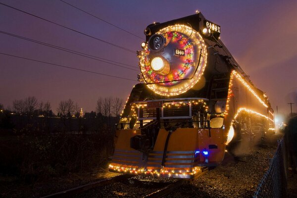 Image d un train en marche dans la nuit avec des guirlandes