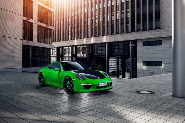 Porsche verde en la acera cerca de un edificio moderno