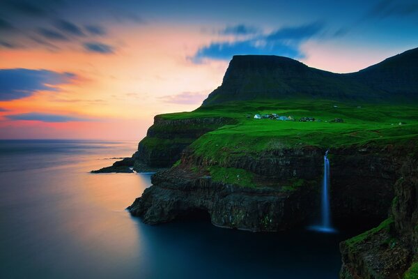 Grünes Gras mit Wasserfall bei Sonnenuntergang