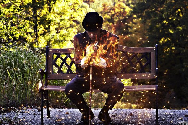 A man sitting on a bench with a fire in his hands