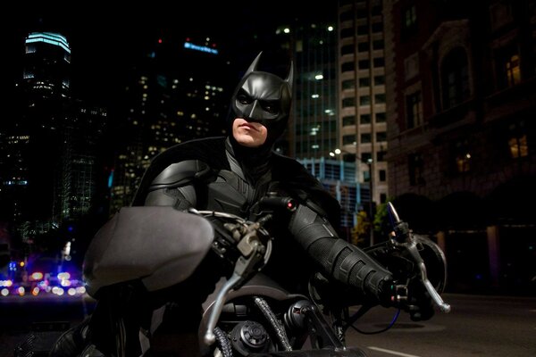 Batman sulla sua moto nera sullo sfondo della città notturna