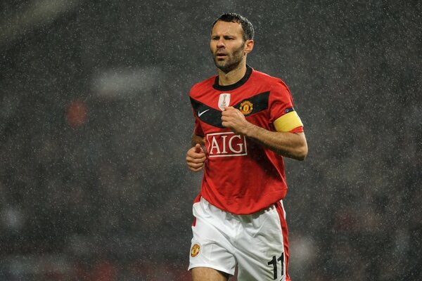 Footballeur en t-shirt rouge courant sous la pluie