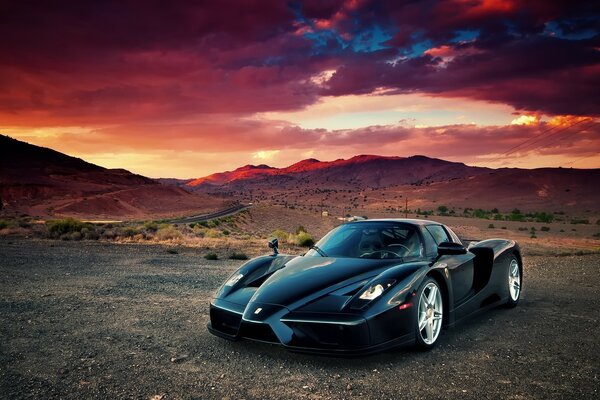 Black fashion racing car in the desert at sunset