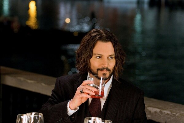 Actor by the water with a glass in his hand