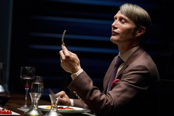 A man alone in a restaurant is sitting at a table with a fork in his hands