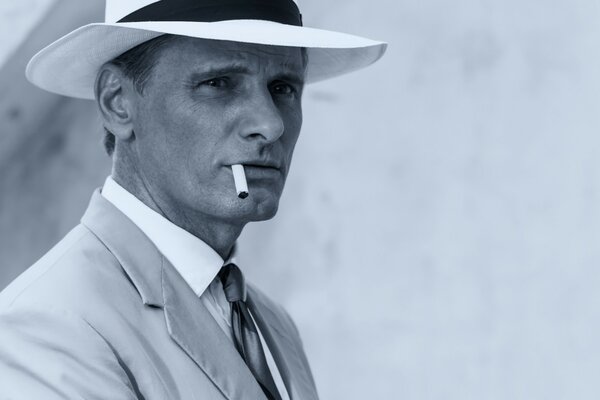 A gentleman with a cigarette and a white hat