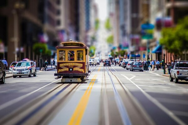 Un tramway traverse la rue au milieu de maisons floues