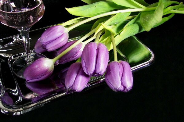Ein Strauß lila Tulpen und ein Glas
