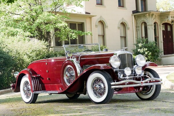 Red retro car on the background of a mansion