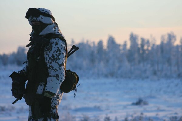 Hombre en camuflaje en el fondo del paisaje invernal