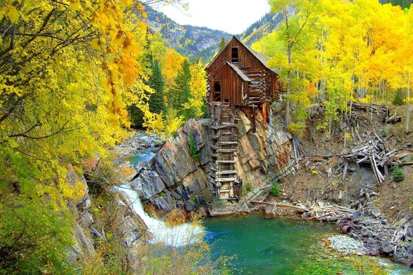 Casa de madera en un acantilado en medio del bosque de otoño