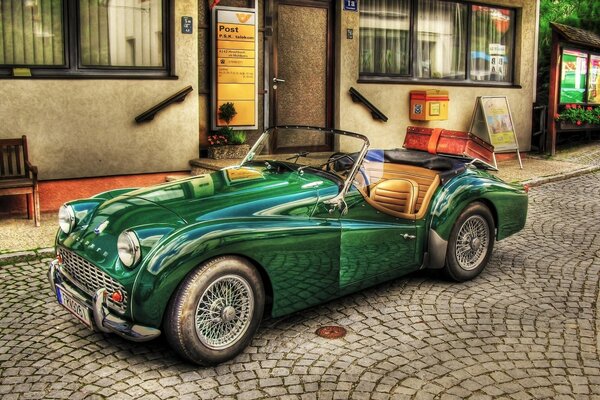 Green convertible on the cobblestones near the building