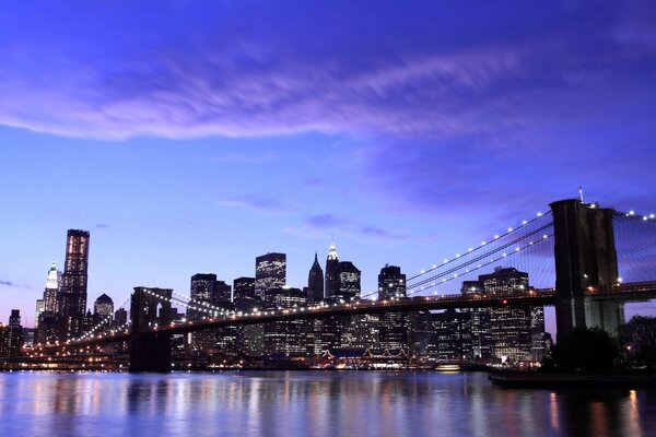 Photo of a large bridge with lights on the background of a modern city