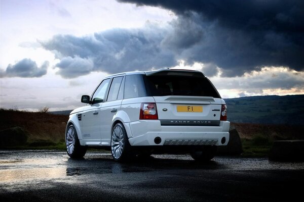 Range rover sur asphalte mouillé sur fond de nuages