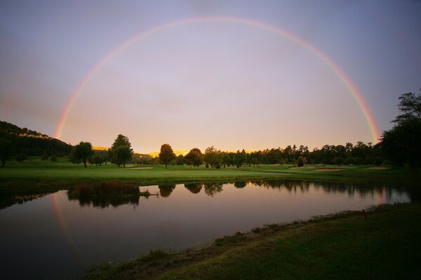 A thin rainbow is reflected in the river