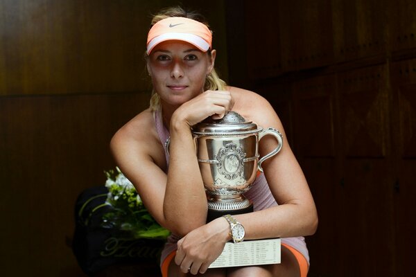 Die Tennisspielerin sitzt mit dem Sportpokal in einer Umarmung