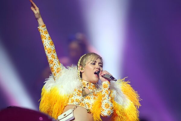 A young singer in an extravagant outfit with artificial fur performs a song on the stage of a music festival