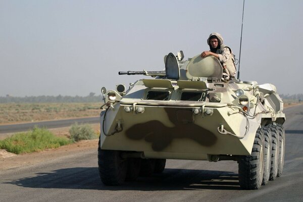 A military man driving an armored personnel carrier on the highway