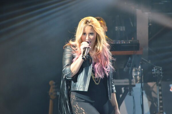 Photo of a blonde singing at a concert with a microphone