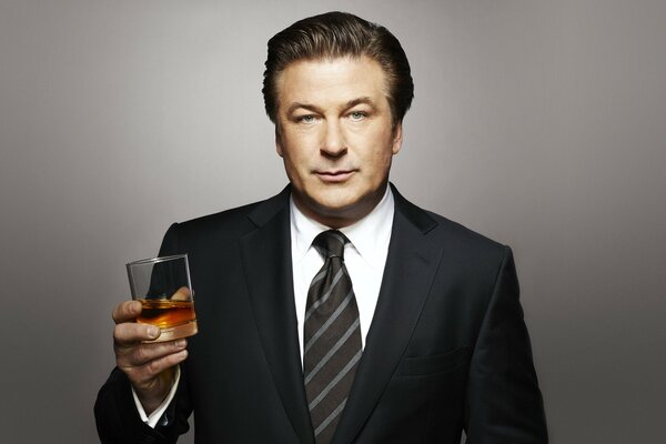 An adult man in a suit with a glass