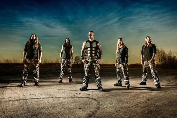 A musical group, long-haired rockers against a dark blue sky