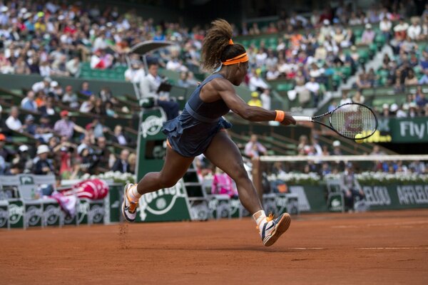 Dark-skinned girl playing tennis at the stadium