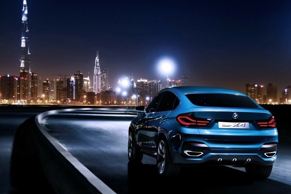 A blue BMW car is driving on the road against the background of a night city
