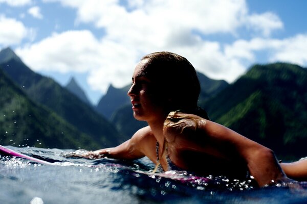 Девушка плавает на доске на фоне высоких гор