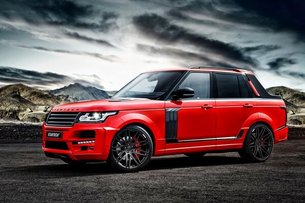 Range rover vermelho contra o céu e as montanhas