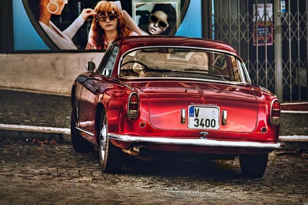 Red retro car on cobblestones