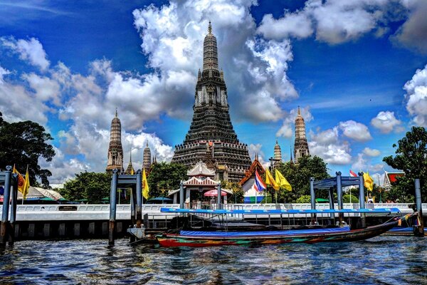 A building with beautiful architecture on the background of a blue sky with clouds on the shore of a reservoir