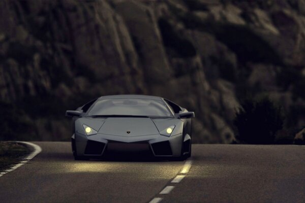 El coche lamborghini corre sobre el asfalto en el fondo borroso de las montañas