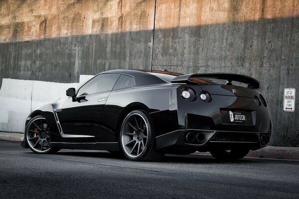 Black Nissan on a gray wall background