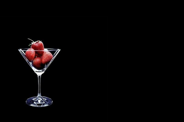 Morangos num copo de martini. Fundo preto. Minimalismo