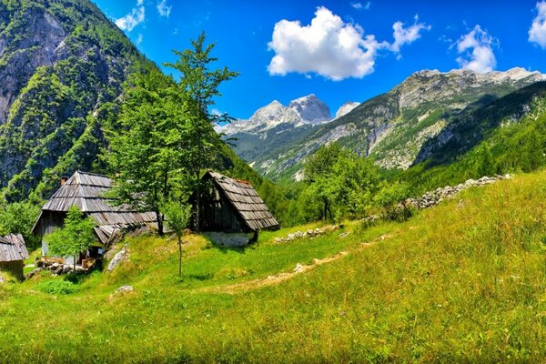 Yeşil dağlarda, açık mavi gökyüzünün altında, bulutlarla dolu evler