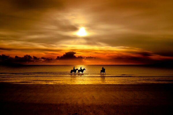 Cavaleiros à beira-mar ao pôr do sol