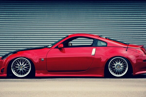 Фотография красного nissan 350z на фоне закрытой роллеты