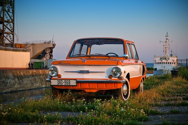 Scarlet retro car on the background of a ship