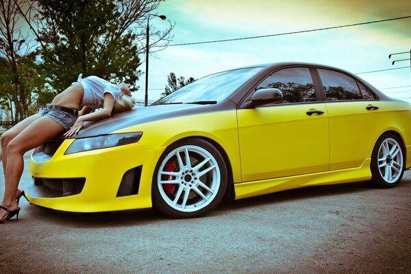 A girl on the hood of a yellow car