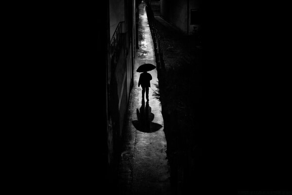 Silhouette eines Mannes unter einem Regenschirm in Schwarz und Weiß