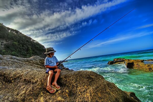 Am Morgen sitzt ein fröhlicher Angler am Meer