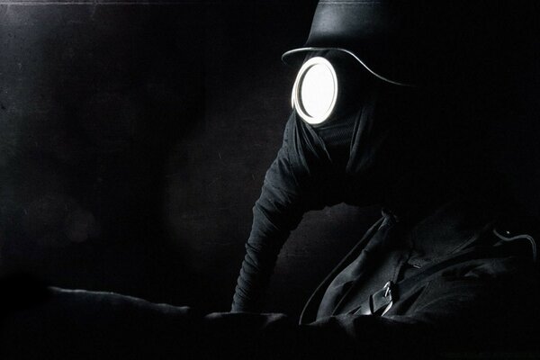 Czarno - białe zdjęcie zamaskowanego mężczyzny na ciemnym tle