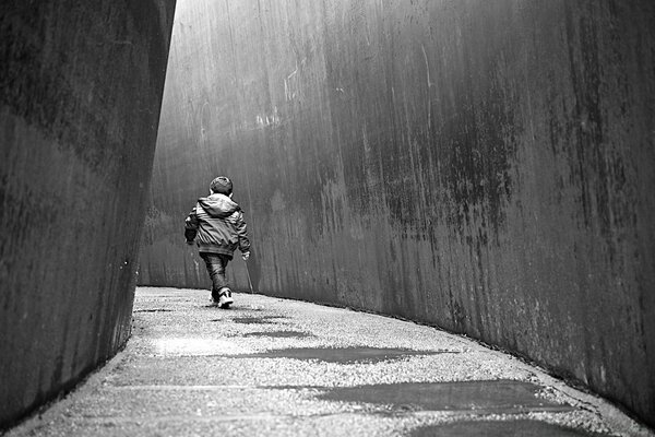 The kid walks alone on the street like an adult